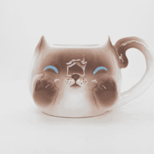 A smiling ceramic Siamese cat mug beckons
